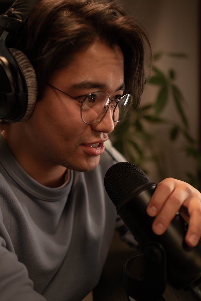 Close-up of sound engineer wearing headphones in a home studio, engaged with a microphone.